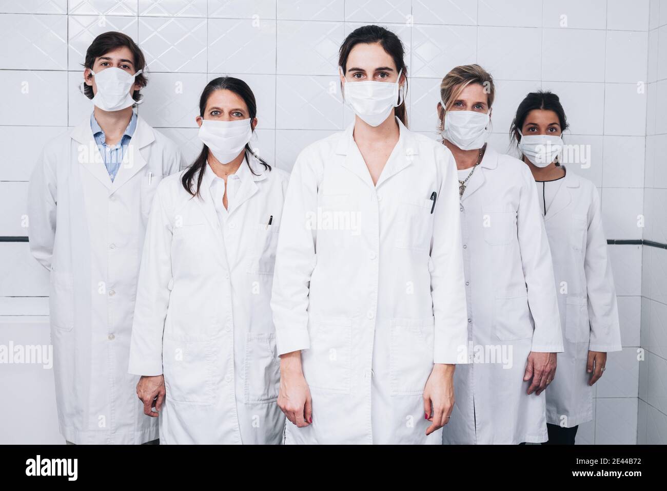 Un gruppo di cinque medici con una maschera sul loro faccia e un cappotto bianco in piedi in un ospedale camera Foto Stock