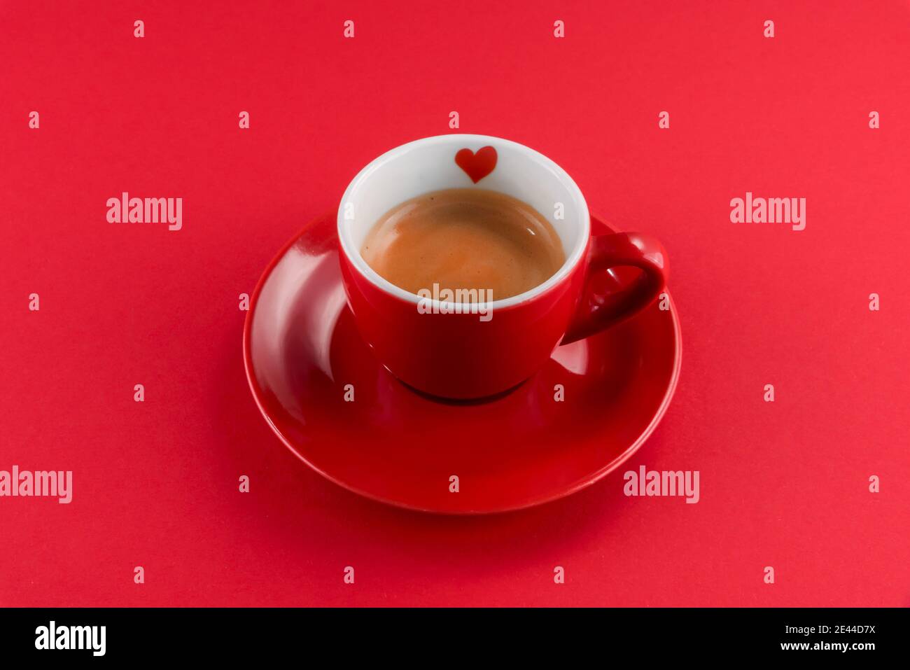 caffè espresso rosso con un po' di cuore su un sfondo rosso Foto Stock