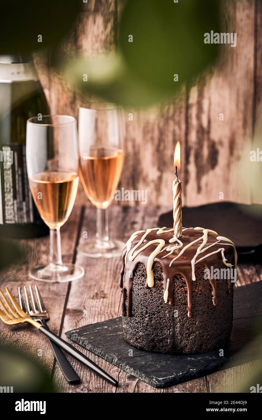Deliziosa torta al cioccolato con candela bruciante servita su tavola di  ardesia sul tavolo con bicchieri di champagne al caffè Foto stock - Alamy