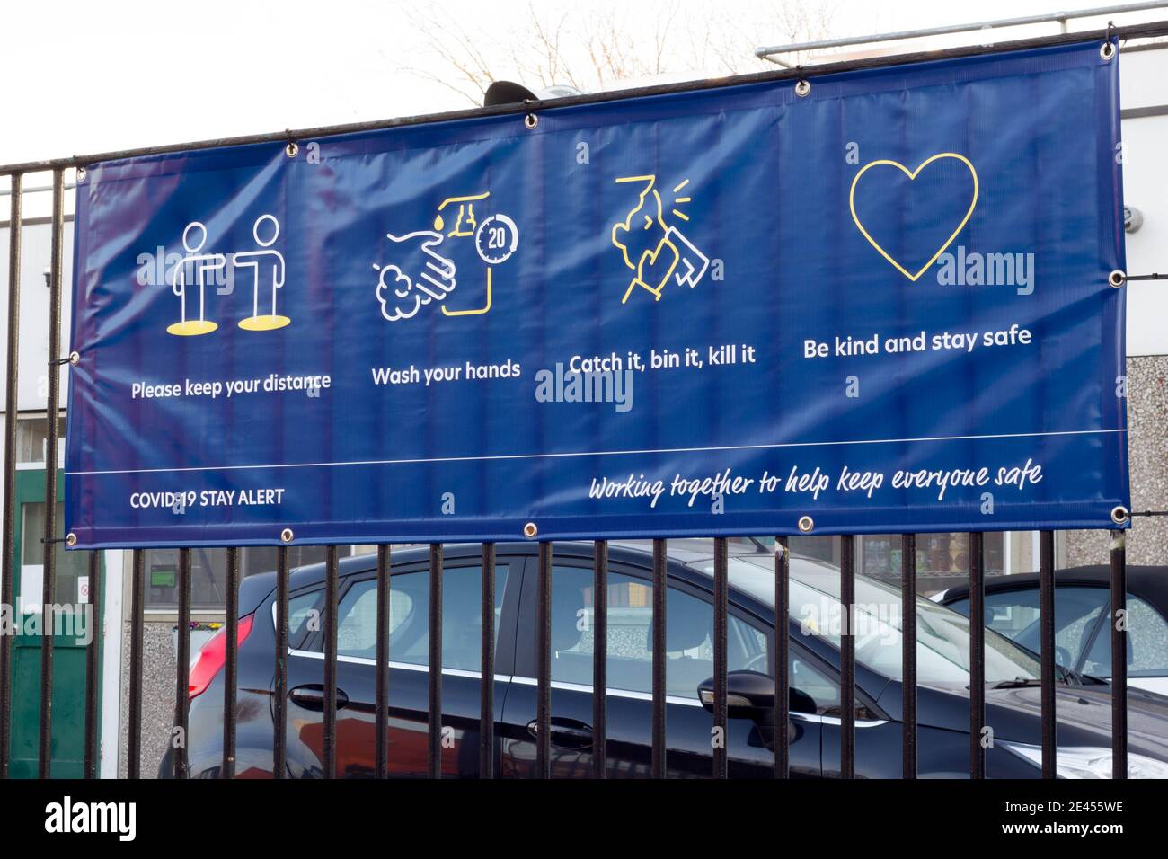 Grande covid-19 banner che invita il pubblico a " essere gentili e stare al sicuro" appendere su recinzione, 'lavorando insieme per aiutare a mantenere tutti al sicuro' Londra Inghilterra Foto Stock