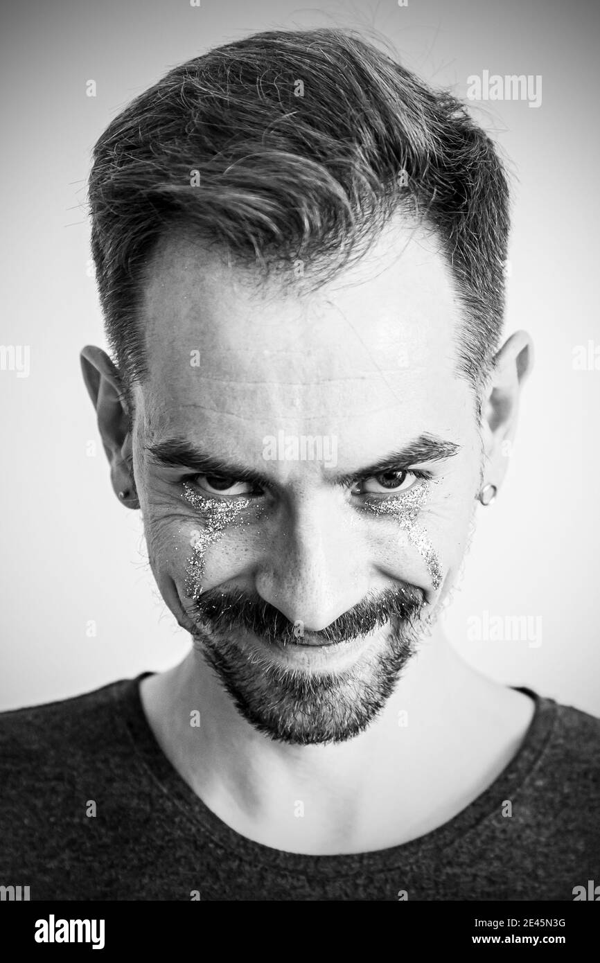 Ritratto di un uomo con un sorriso creepy e scintilla sotto gli occhi. Bianco e nero Foto Stock