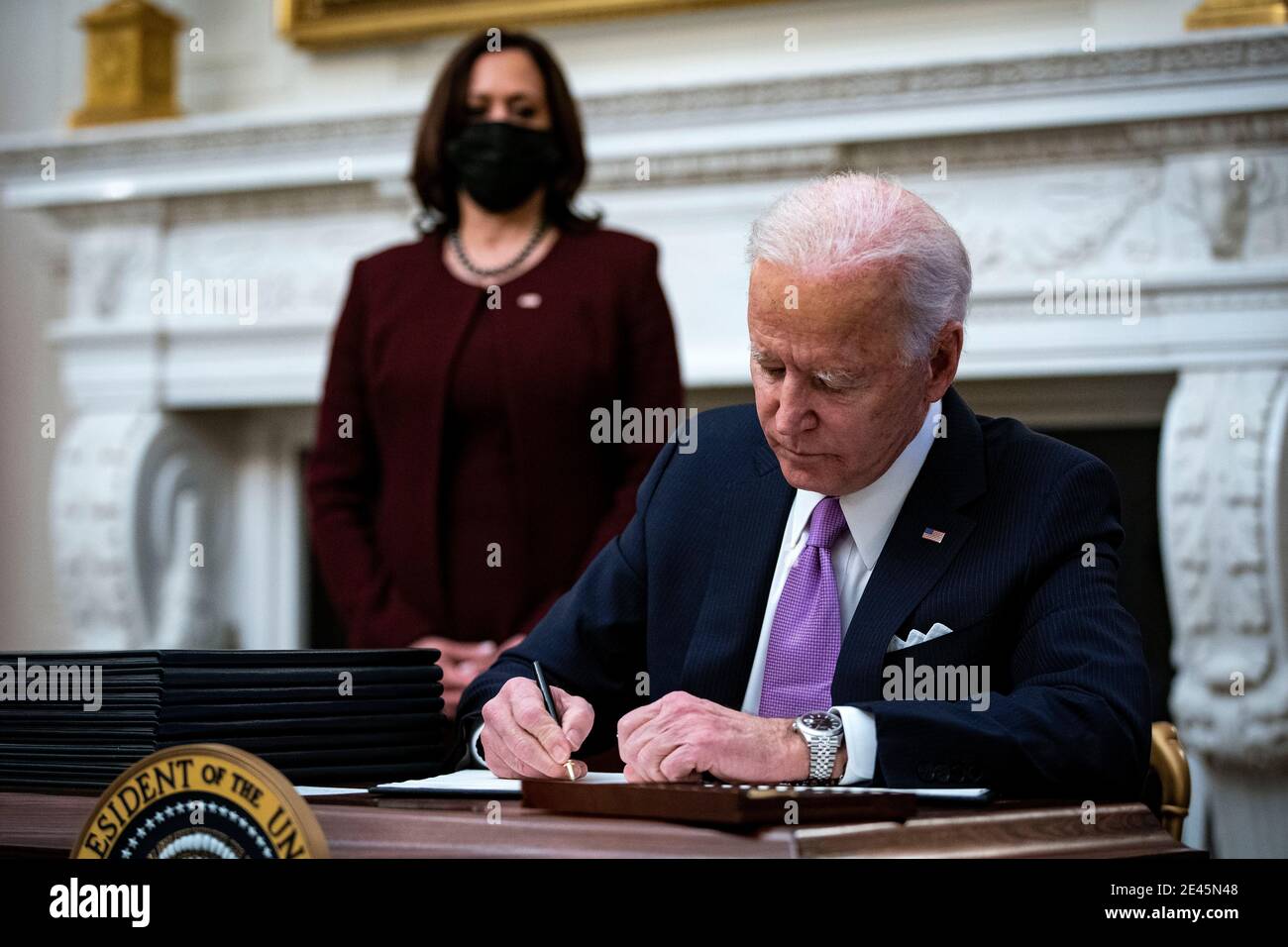 Il presidente degli Stati Uniti Joe Biden firma un ordine esecutivo dopo aver parlato durante un evento sulla risposta del Covid-19 della sua amministrazione con il vice presidente degli Stati Uniti Kamala Harris, ha lasciato, nella Sala da pranzo di Stato della Casa Bianca a Washington, DC, Stati Uniti, giovedì 21 gennaio 2021. Biden nel suo primo giorno intero in carica ha in programma di emettere un ampio insieme di ordini esecutivi per affrontare la pandemia di Covid-19 che rapidamente invertirà o ridisegnerà molte delle politiche più fortemente criticate del suo predecessore. Credit: Al Drago/Pool via CNP | utilizzo in tutto il mondo Foto Stock