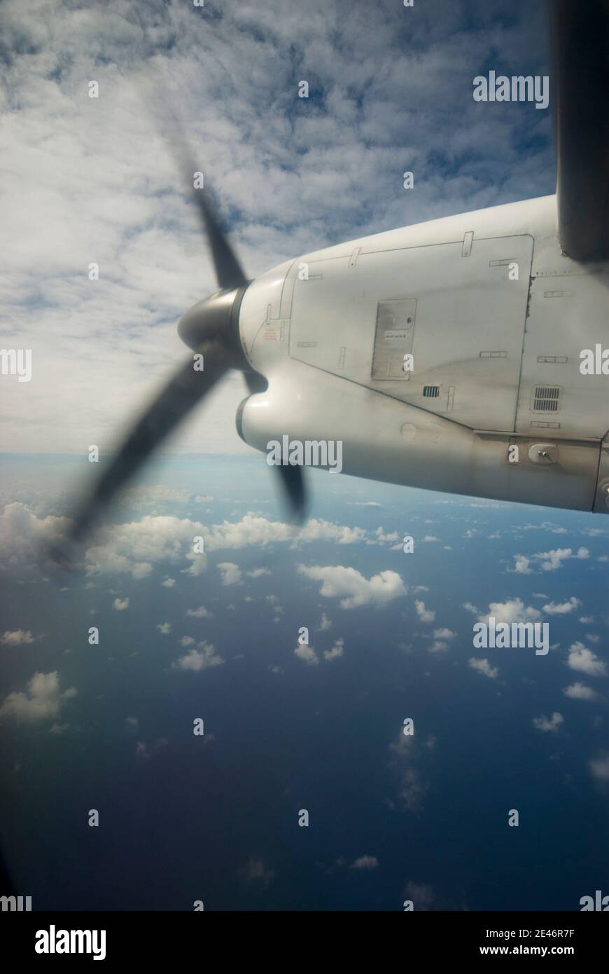 L'aereo propellerà l'ala contro un cielo nuvoloso e sull'oceano Foto Stock