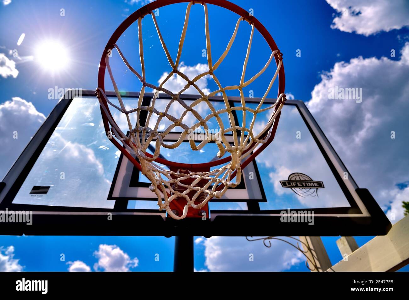 Vista su una rete da basket e sullo sfondo contro il cielo blu con una stella solare Foto Stock