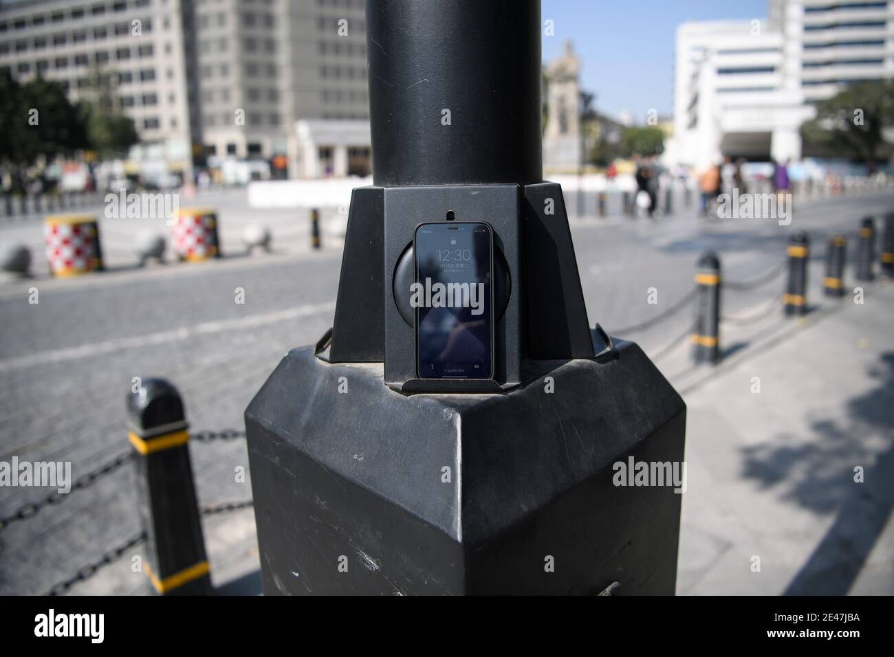 Un gadget fornisce la ricarica wireless per smartphone di pedoni sono visti attaccati ad una lampione nella città di Guangzhou, Cina meridionale¯s Guangdong provincia Foto Stock