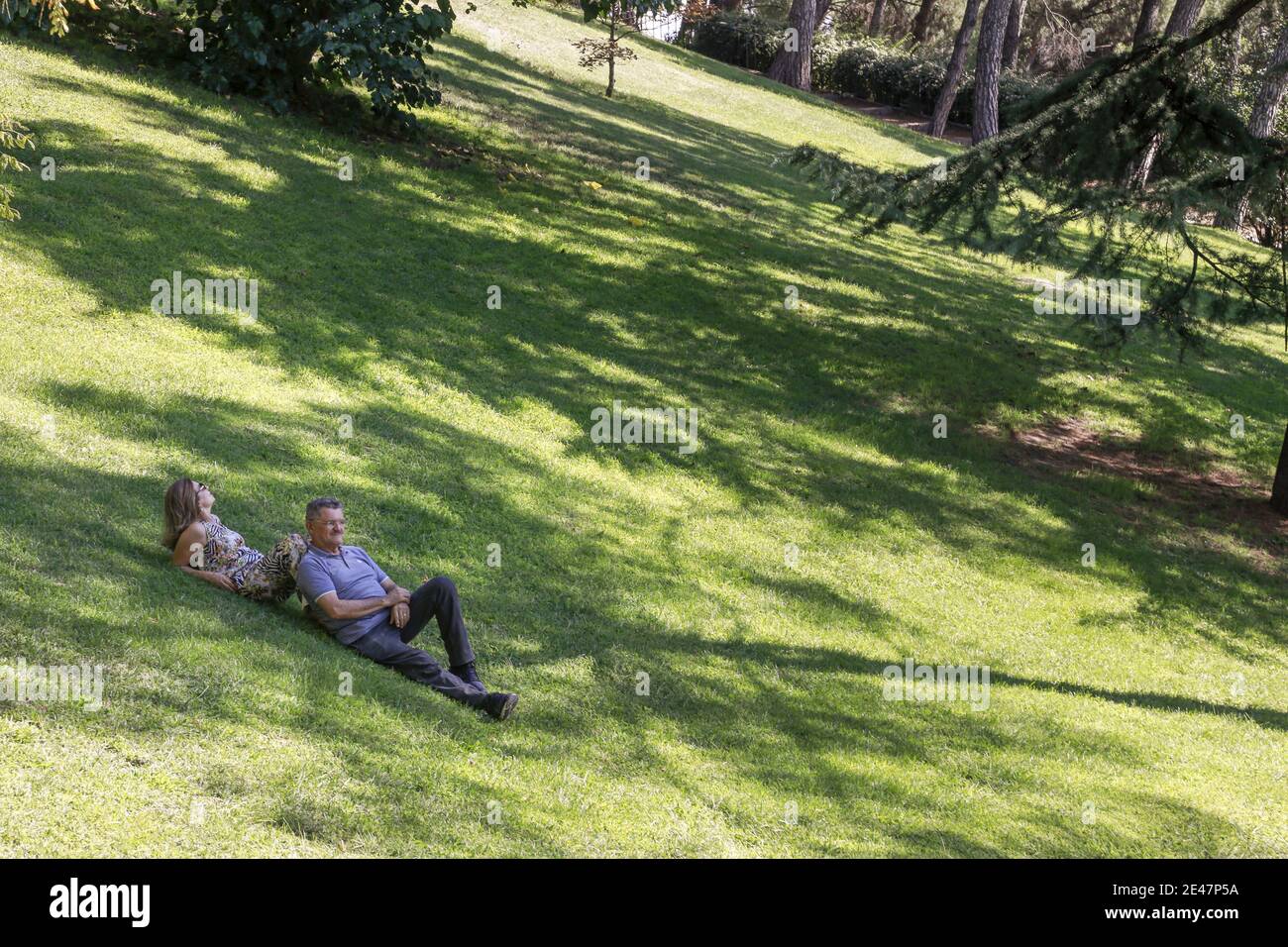 Coppia di mezza età che giace su erba verde su una collina e. parlare Foto Stock