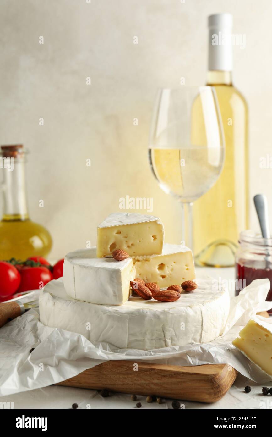 Concetto di cucina gustosa con camembert, nocciole e vino su un tavolo bianco, formaggio camembert, una degustazione di camembert e vino Foto Stock