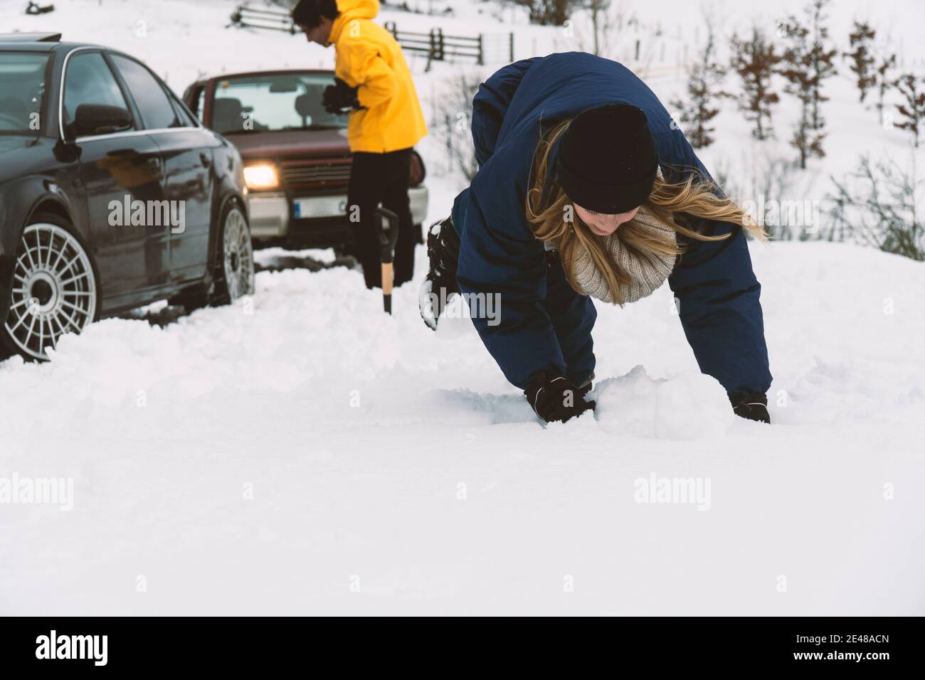 Due amici che lottano con palle di neve nella neve con il auto 4wd sullo sfondo Foto Stock