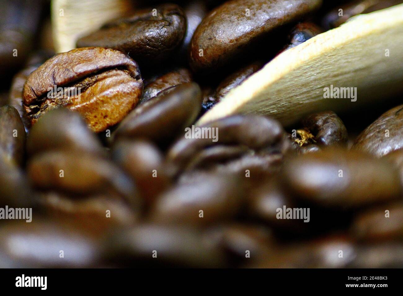 Macro primo piano di alcuni fagioli di caffè arrosto in e. Intorno ad una piccola sessola di legno Foto Stock