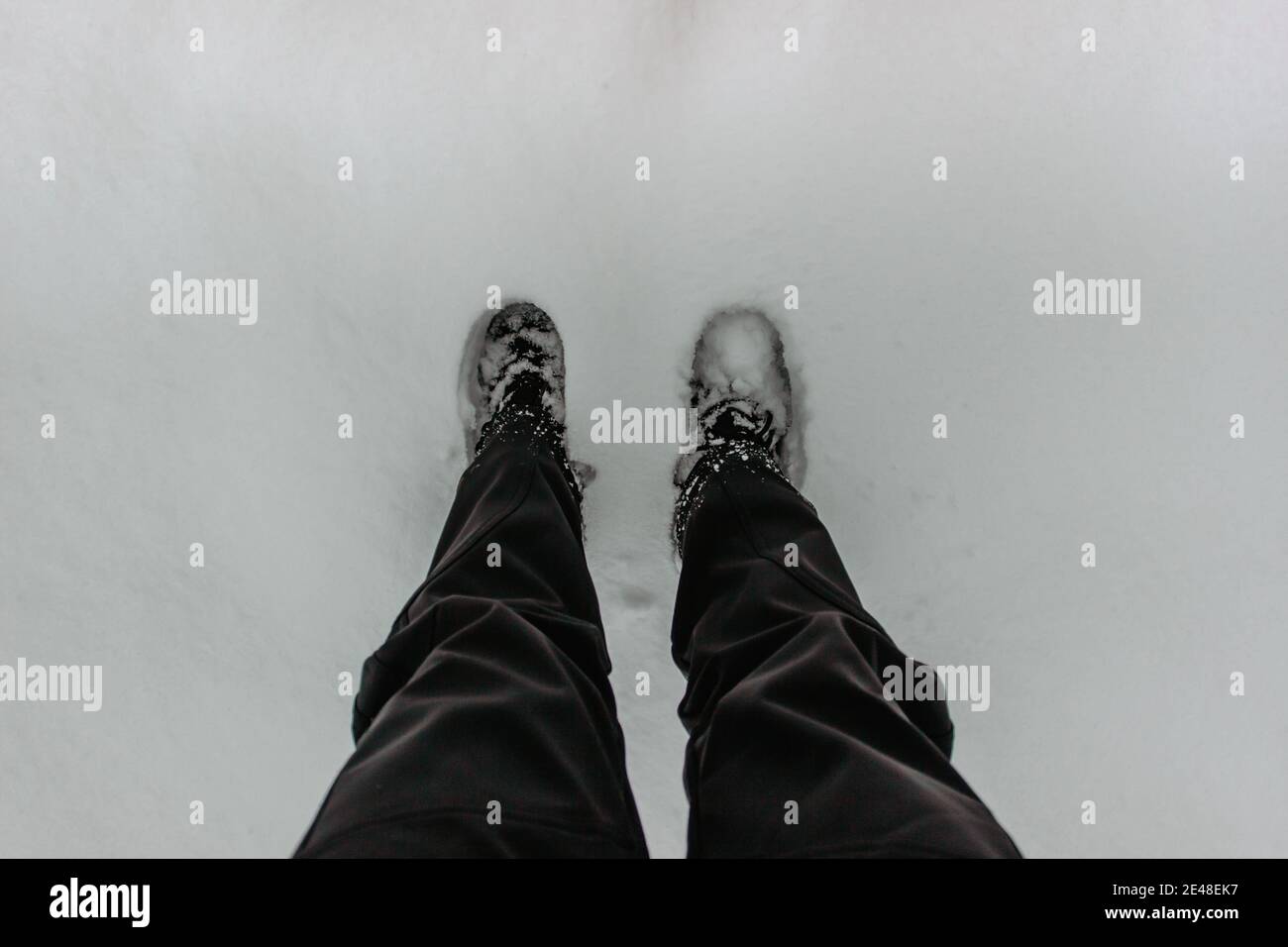 Dettaglio di stivali caldi impermeabili in neve fresca profonda.piedi femminili in scarpe nere, passeggiate invernali in neve.Vista ad alto angolo delle gambe in piedi femmina con sno Foto Stock