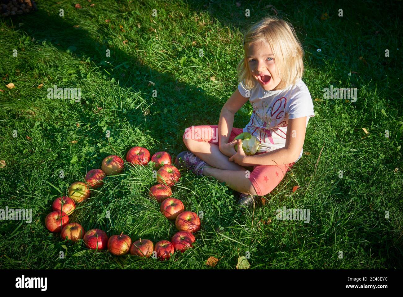 Bambina sull'erba con cuore forma da fresco mele Foto Stock