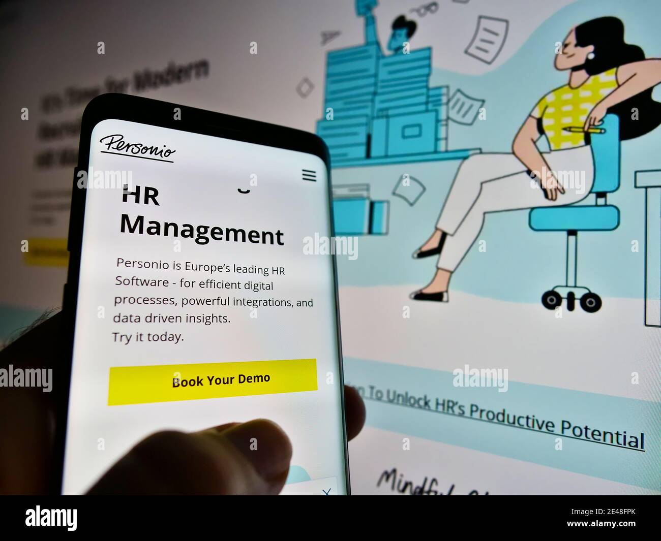Persona titolare del telefono con sito web e logo della società tedesca di sviluppo software HR Personio GmbH su schermo. Mettere a fuoco in alto a sinistra del display del cellulare. Foto Stock
