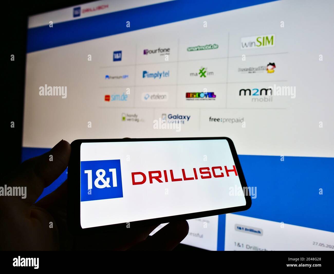 Persona che tiene il telefono con il logo del fornitore tedesco di telecomunicazioni 1und1 Drillisch AG in esposizione. Concentrarsi al centro dello schermo dello smartphone. Foto Stock