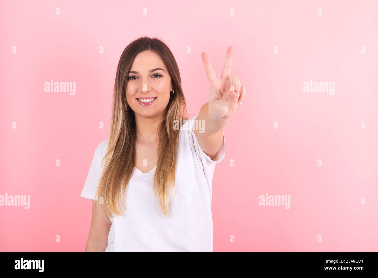 Giovane donna che fa un gesto di vittoria con la mano Foto Stock