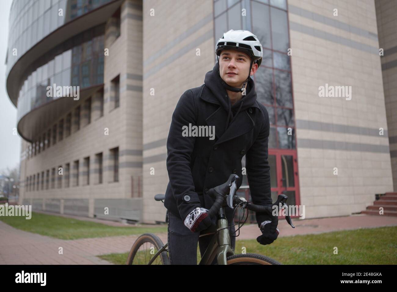 Giovane uomo che indossa un casco da bicicletta mentre si pedalano per le strade della città Foto Stock