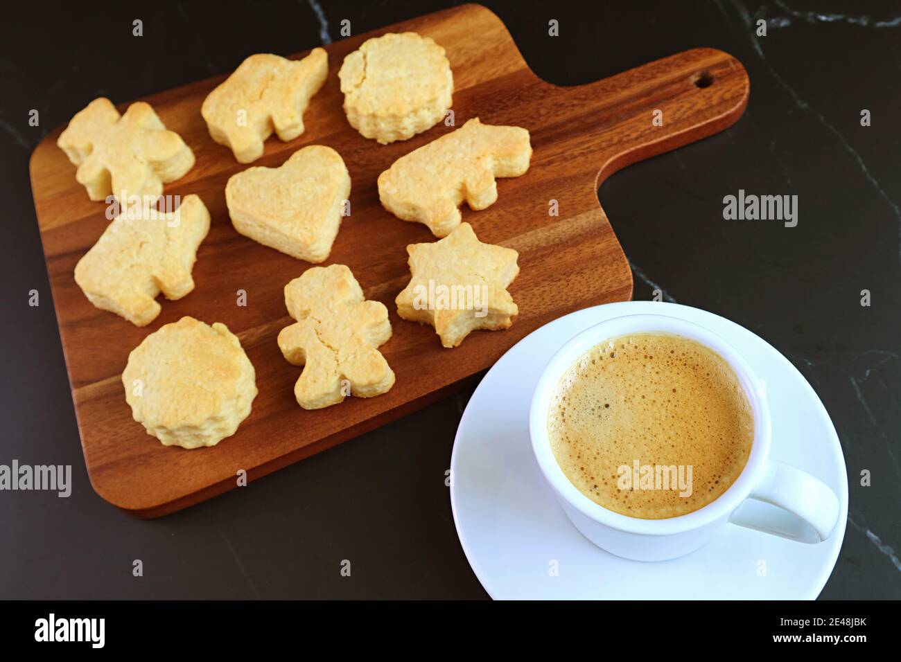 Tazza di caffè caldo con delizioso assortimento a forma di animale Cookie su tavola nera Foto Stock
