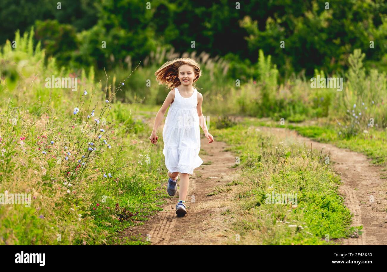 Ragazza piccola felice che corre lungo il percorso Foto Stock