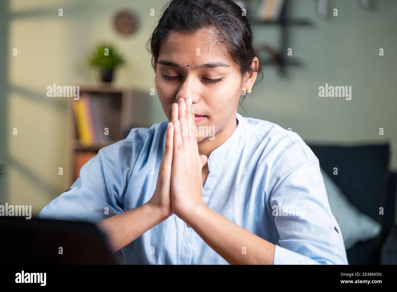 Giovane donna di affari che prega di fronte al portatile dopo il completamento del test online o l'esame per i risultati - concetto di credere, gratitudine in dio Foto Stock