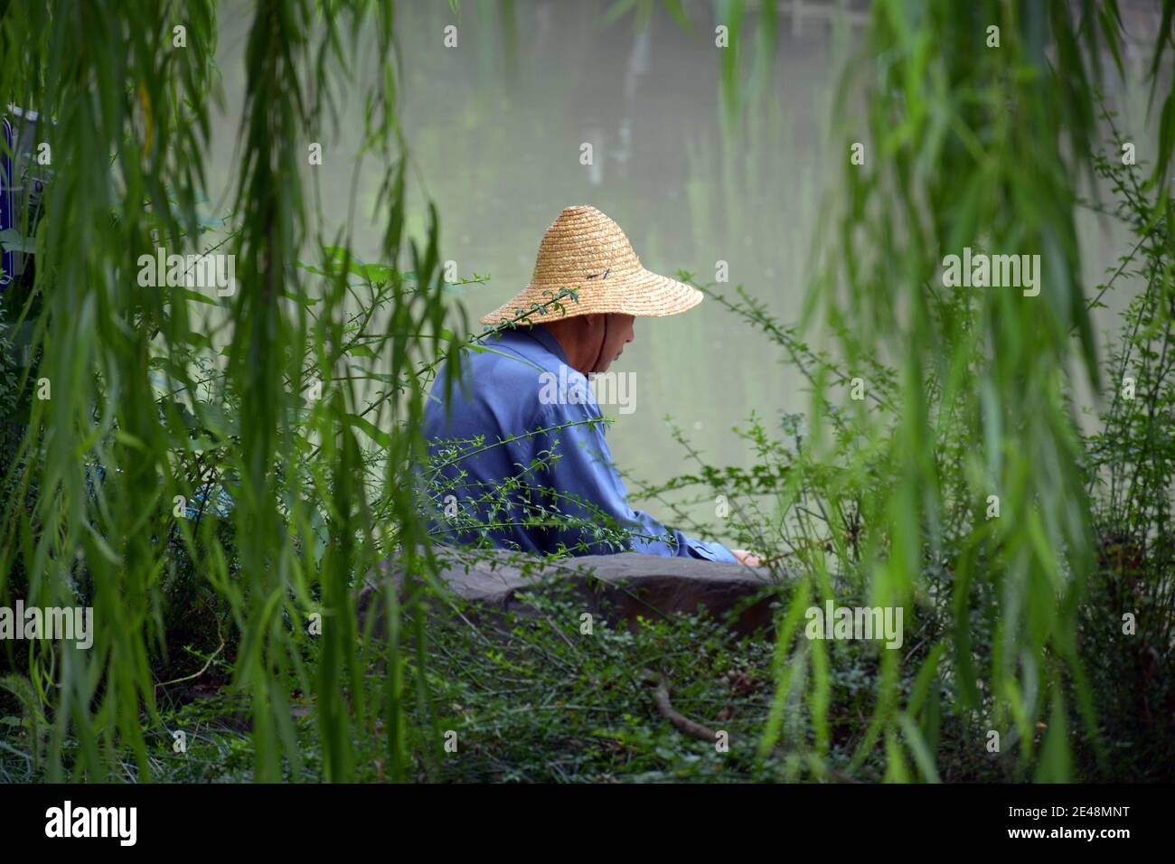 In Jiaxing un uomo pesca dalla riva del vecchio grande canale che corre da Pechino a Hangzhou. La gente avrebbe pescato qui da molti anni Foto Stock