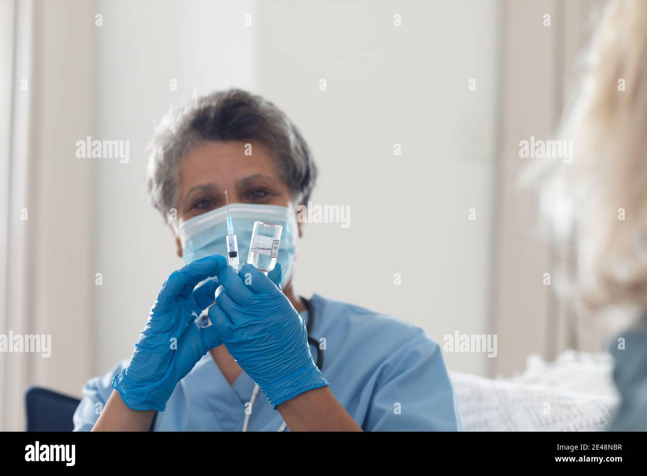 Senior african american femmina medico indossando maschera viso preparazione della vaccinazione a casa Foto Stock