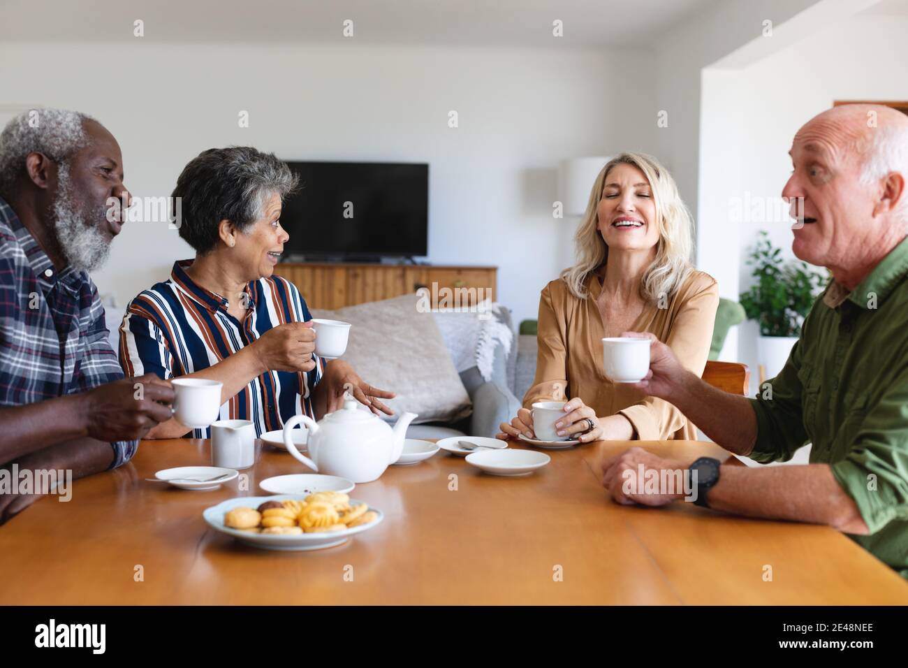 Coppie caucasiche e afroamericane senior seduti a tavola bevendo tè a casa Foto Stock