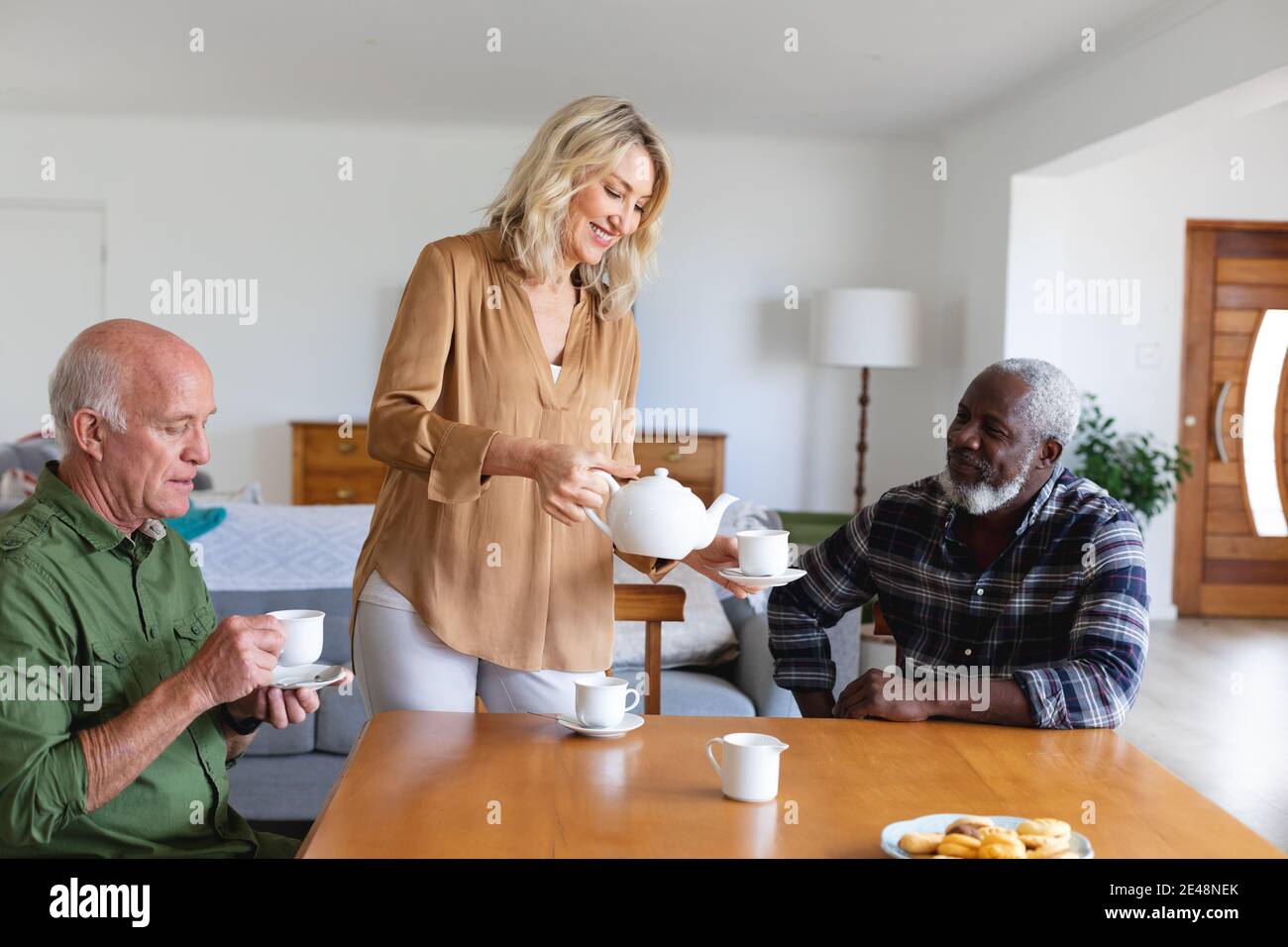 Coppie caucasiche e afroamericane senior seduti a tavola bevendo tè a casa Foto Stock