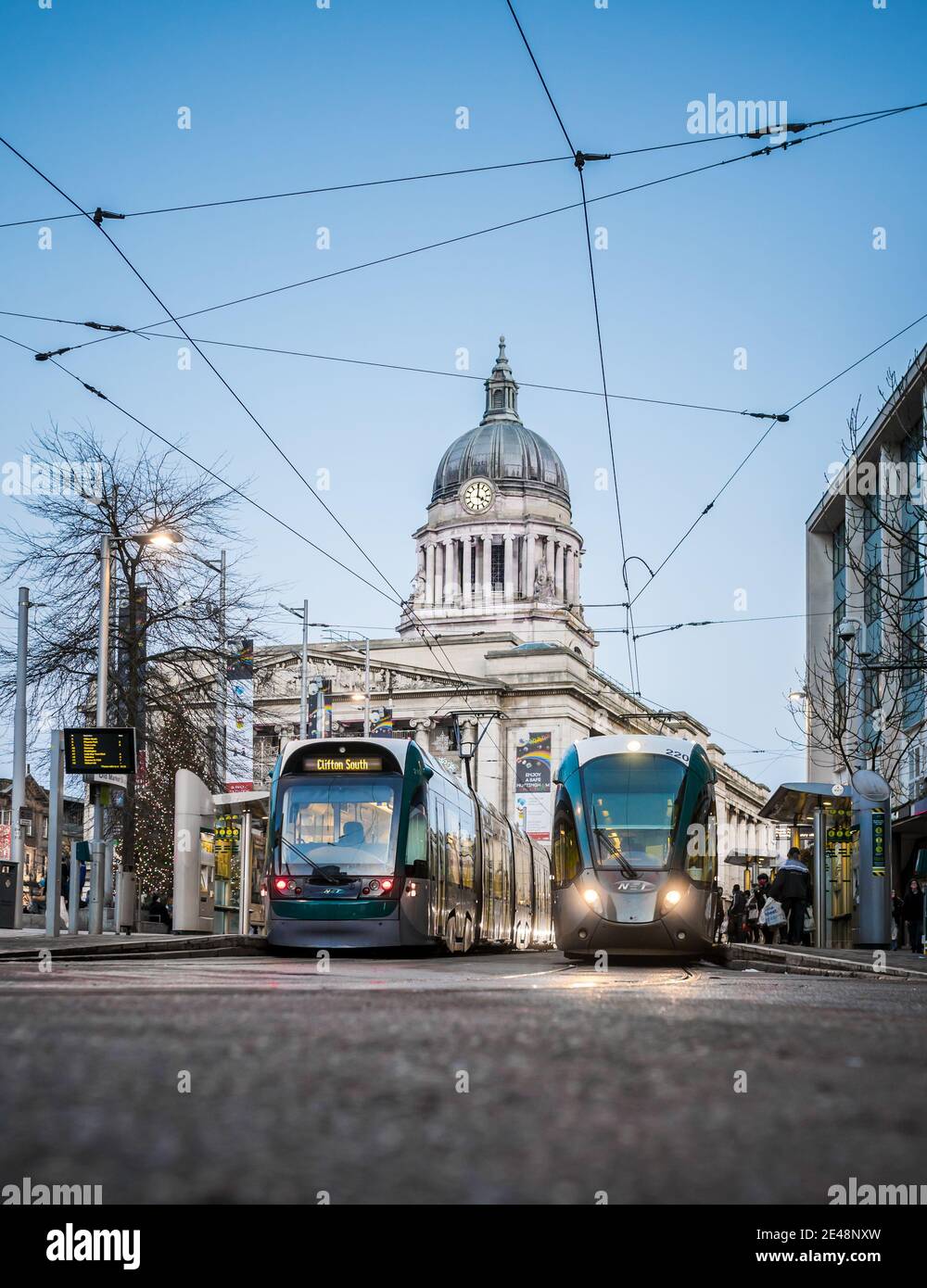 Nottingham UK centro città shopping Trams council house illuminato con tram parcheggiato di fronte illuminato ai lam di strada notturna e cavi treno in attesa Foto Stock