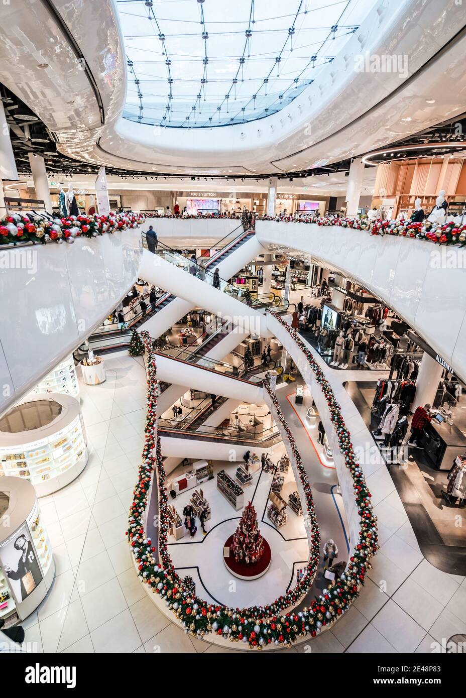 Grandi magazzini molto affollati con acquirenti su numerose scale mobili simmetriche Linee di simmetria Bright Natale acquirenti gennaio vendite su più piani Foto Stock
