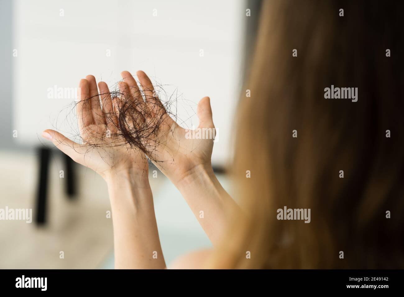 Giovane donna che tiene i capelli di perdita nelle mani Foto Stock