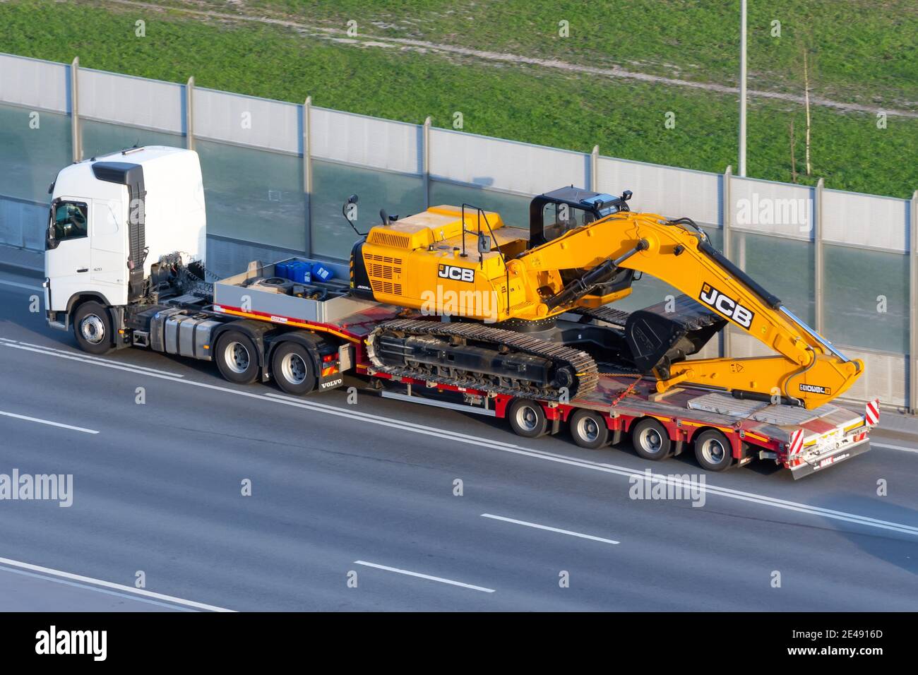 Escavatore rimorchio JCB camion caricato sul trasporto di carico su una piattaforma rimorchio autostrada urbana. Russia, San Pietroburgo. 07 maggio 2020 Foto Stock