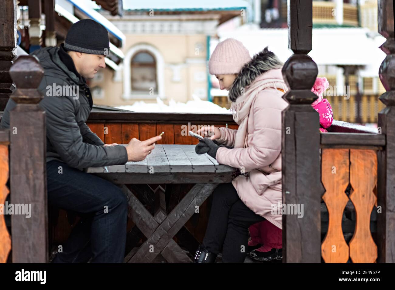 Una coppia sta aspettando il suo ordine per il pranzo in un caffè di strada, testando per telefono. Comunicazione con le persone su uno smartphone Foto Stock