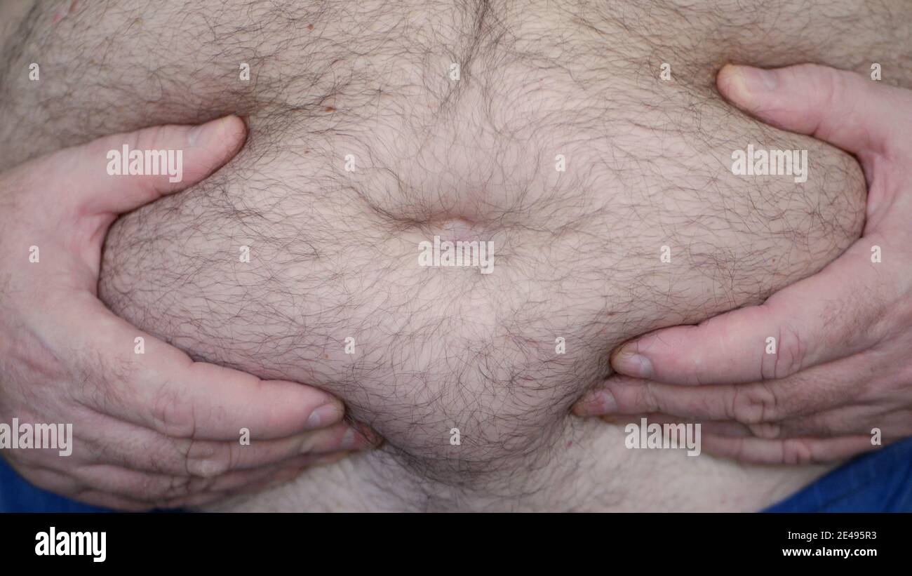 L'uomo obese che mostra il suo venticcio grasso, una persona affamata che misura il suo grasso venticcio con le sue mani, problemi di salute dell'uomo anziano con l'obesità Foto Stock