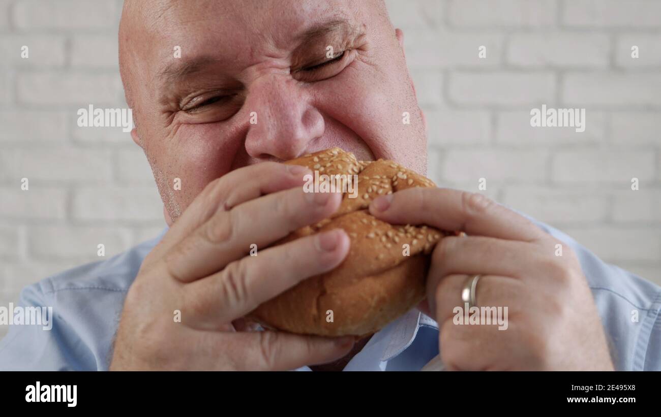 Fame Man mangiare un hamburger gustoso, gustare un delizioso spuntino in un ristorante fast food Foto Stock