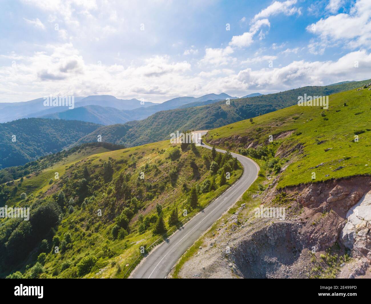 Vista aerea della caccia di un camion e di due auto su strada di passaggio di montagna con bella foresta Foto Stock