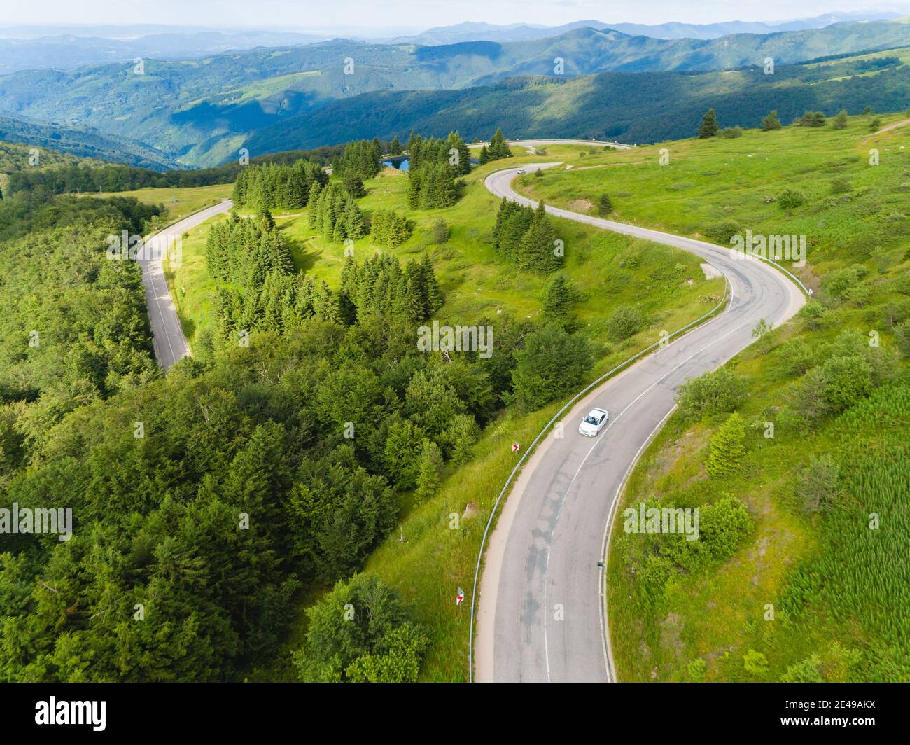 Drone seguire auto bianca su strada di passaggio di montagna con bella foresta Foto Stock
