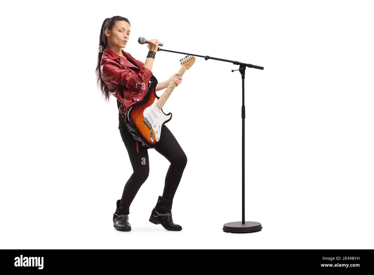 Giovane cantante femminile con una chitarra elettrica e un microfono su un supporto isolato su sfondo bianco Foto Stock