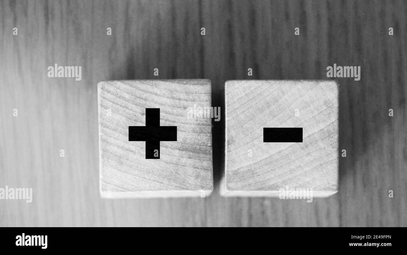 I segni più e meno sui cubetti di legno sul tavolo di legno. Concetto di soluzione aziendale. Foto Stock
