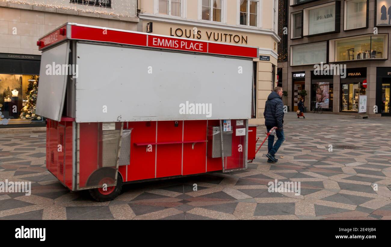 Copenhagen, Danimarca - 12 Dic 2020: Un uomo che cammina con un tradizionale carrello hot dog nel centro della città. Foto Stock