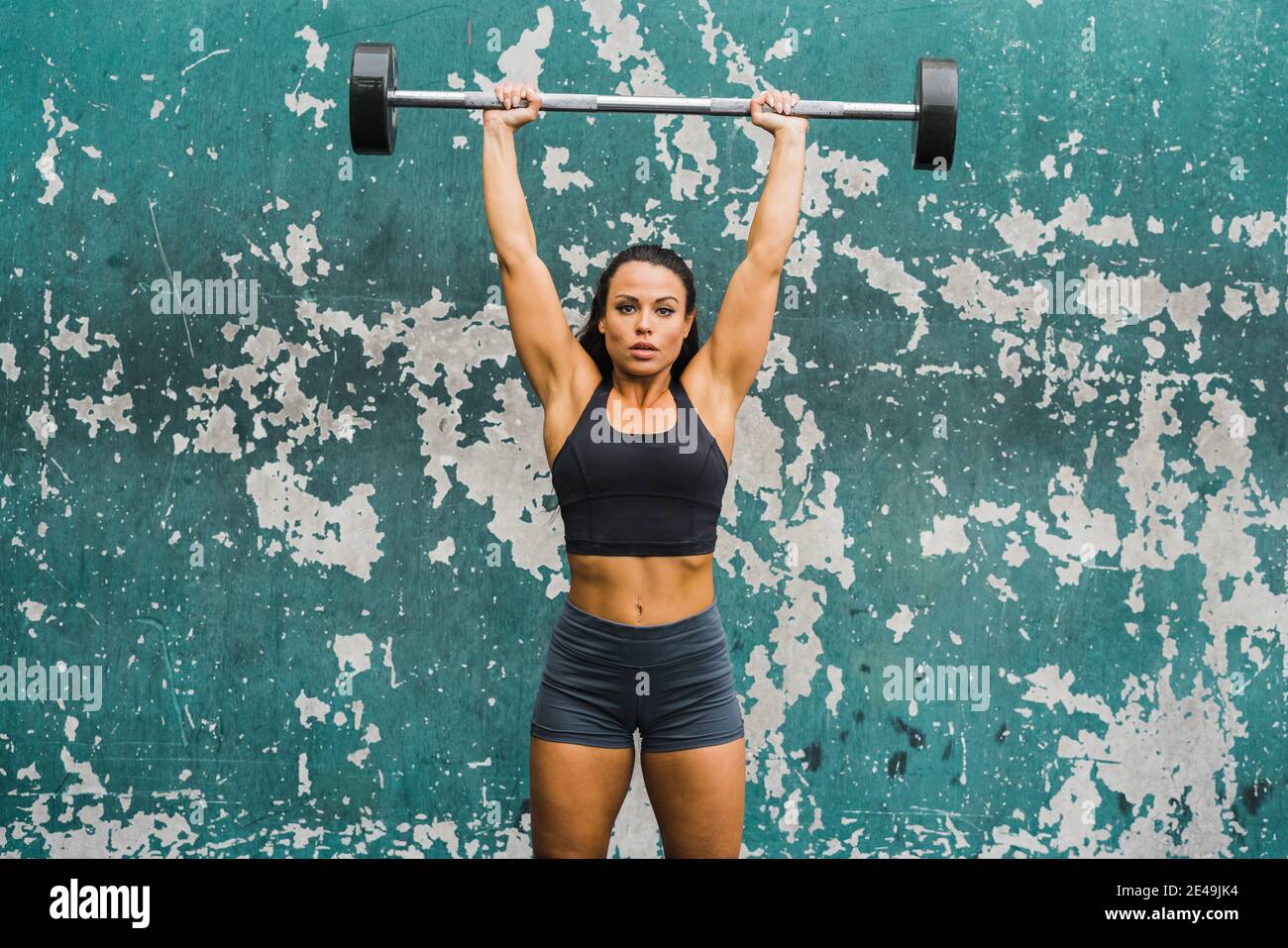 atleta femminile che esegue la pressa della spalla alla parete della palestra esterna Foto Stock