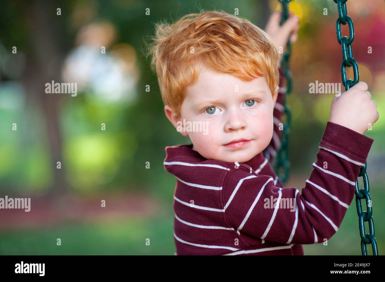 Primo piano di un ragazzo di 3-4 anni che dondola rotazione degli pneumatici all'esterno Foto Stock