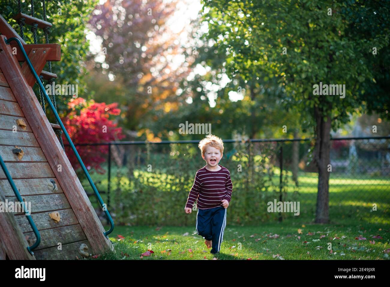 Maschio caucasico di 3-4 anni che corre in erba in cortile sorridente Foto Stock