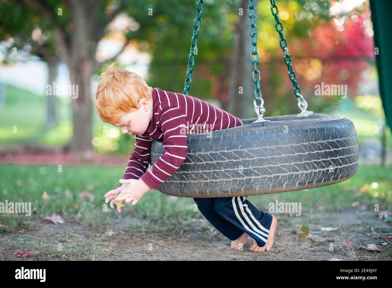 Ragazzo 3-4 anni swing sullo stomaco su swing pneumatico in cortile Foto Stock