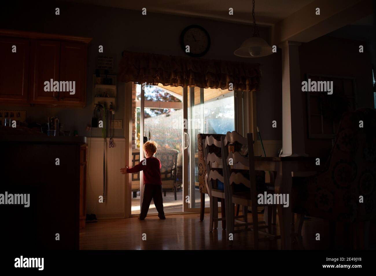 Ragazzo 3-4 anni apertura porta in cucina in bella luci e ombre Foto Stock