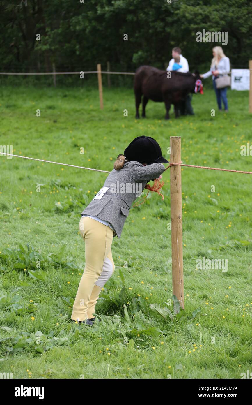 Straiton, Ayrshire, Scozia, Regno Unito 10 giugno 2017. Spettacolo agricolo locale. La bambina in abiti da cavalcare si appoggia sulla corda che guarda annoiata e alimentata! Foto Stock