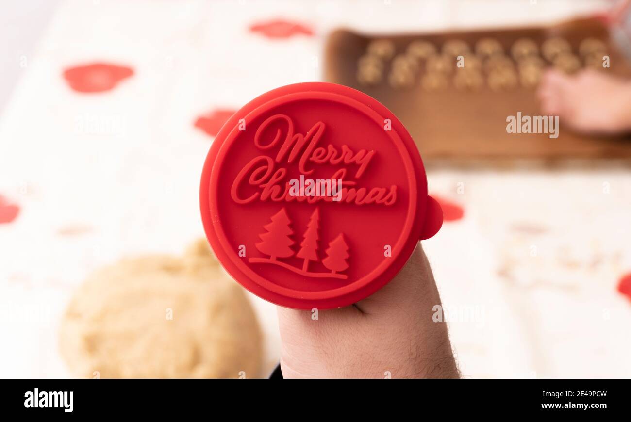 Giovane donna che fa la panetteria tedesca di natale a casa in cucina, buon Natale segno in primo piano Foto Stock