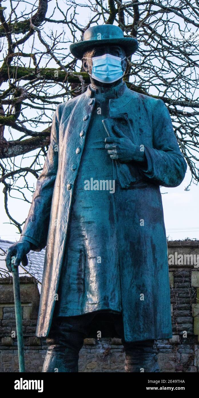 Maschera di coronavirus su una statua di James Rice Buckley. Llandaff, Cardiff, Regno Unito Foto Stock