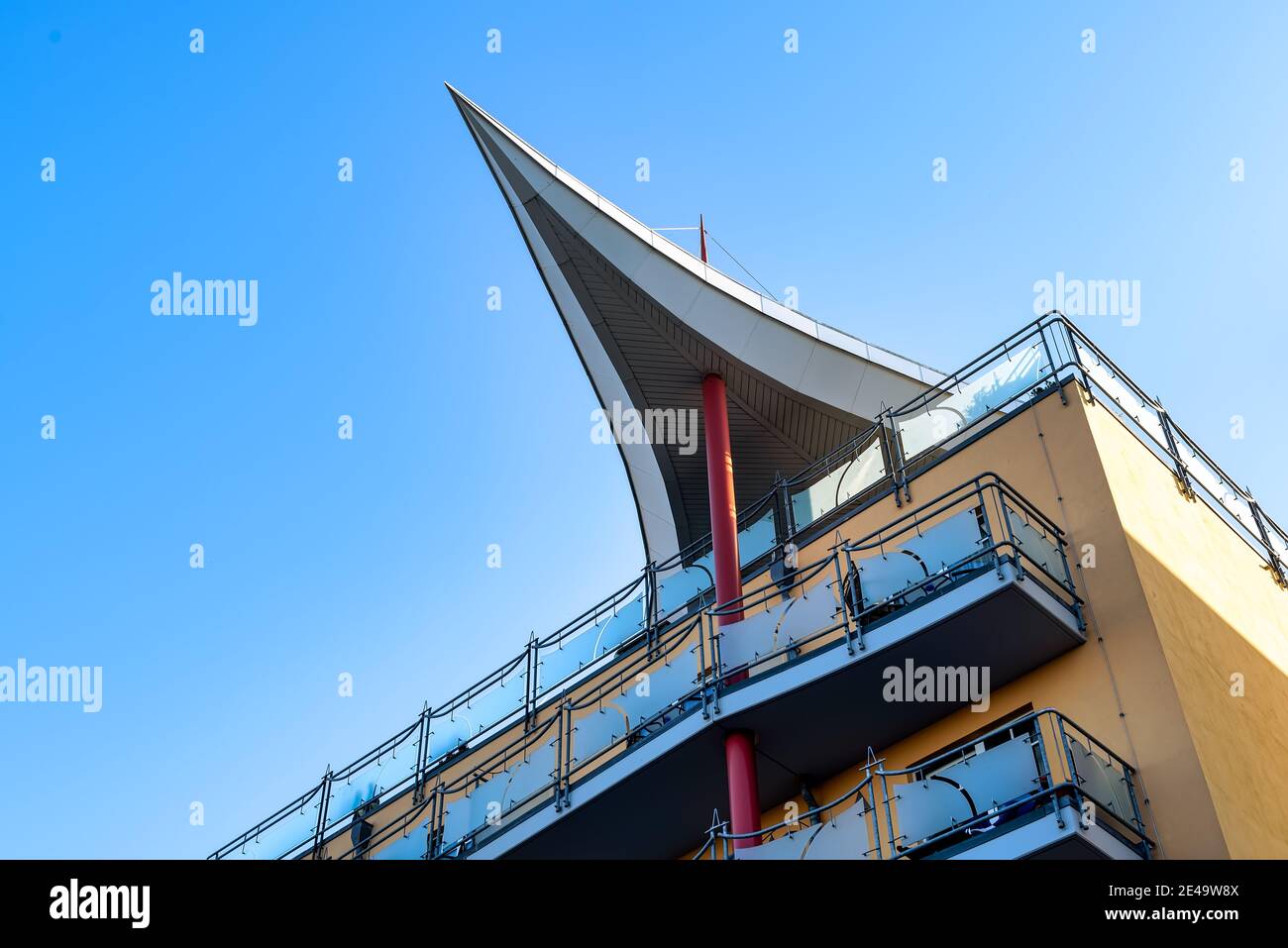 Edificio moderno con balconi e una straordinaria struttura a tetto a forma di vela supportata da una colonna. Foto Stock