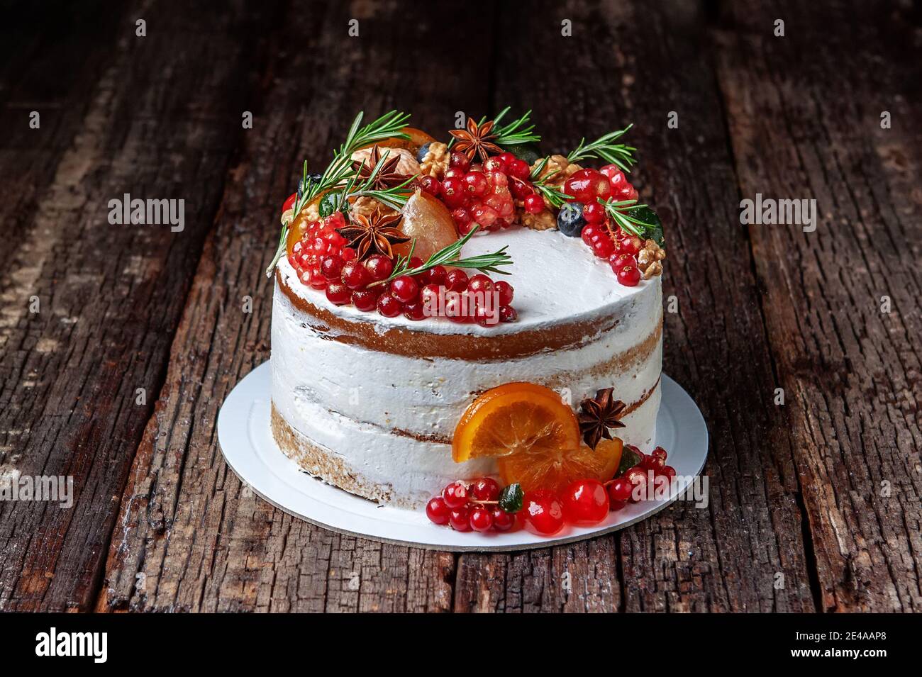 Gustosa torta dolce decorata con frutta e rosmarino, posta su vecchio tavolo rustico. Foto Stock
