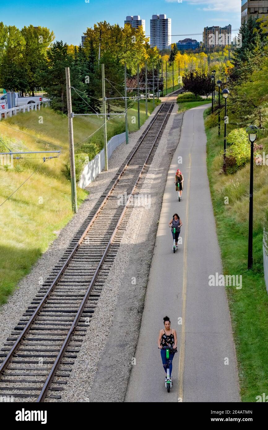 Giovani donne che cavalcano scooter elettrici noleggiati, Edmonton, Alberta, Canada Foto Stock