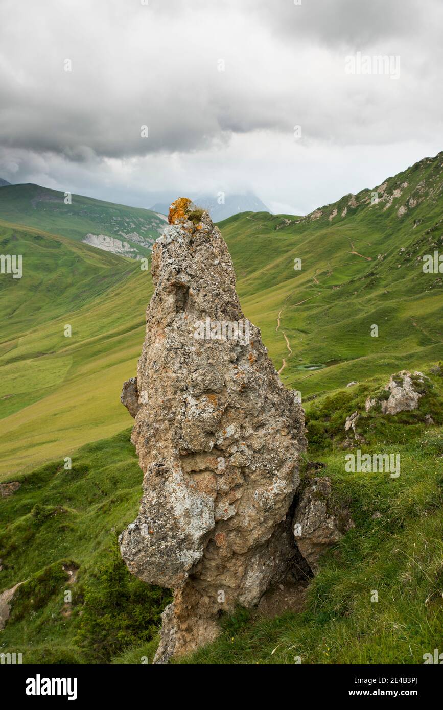 Coni di roccia di fronte ad un prato di montagna, nuvoloso Foto Stock